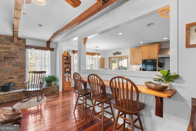 interior space with wood-type flooring, oven, lofted ceiling, and light brown cabinets