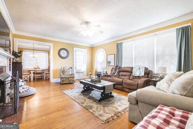 living room featuring a textured ceiling, ceiling fan, hardwood / wood-style flooring, and ornamental molding