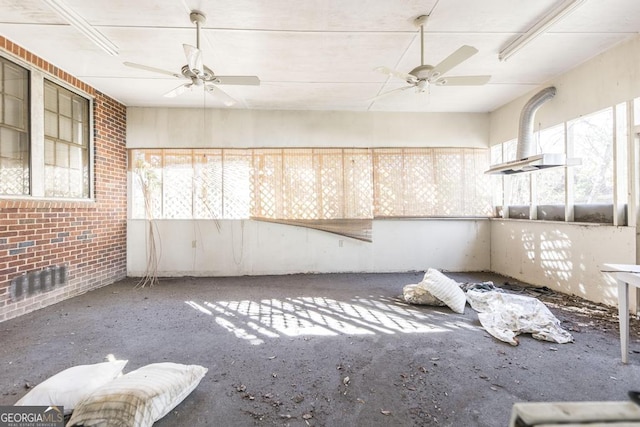 interior space with ceiling fan and brick wall