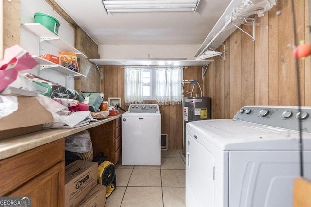 laundry area with washing machine and dryer, wood walls, light tile patterned floors, and electric water heater