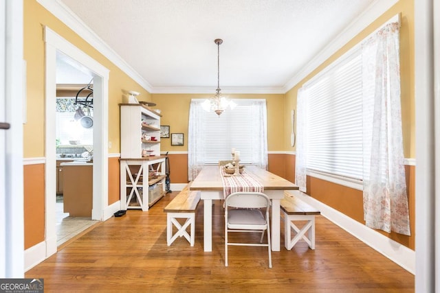 dining area featuring an inviting chandelier, ornamental molding, and hardwood / wood-style floors