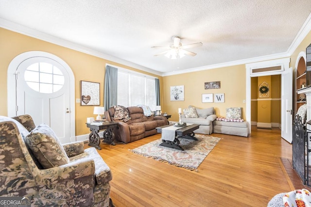 living room featuring a textured ceiling, ceiling fan, hardwood / wood-style flooring, and ornamental molding