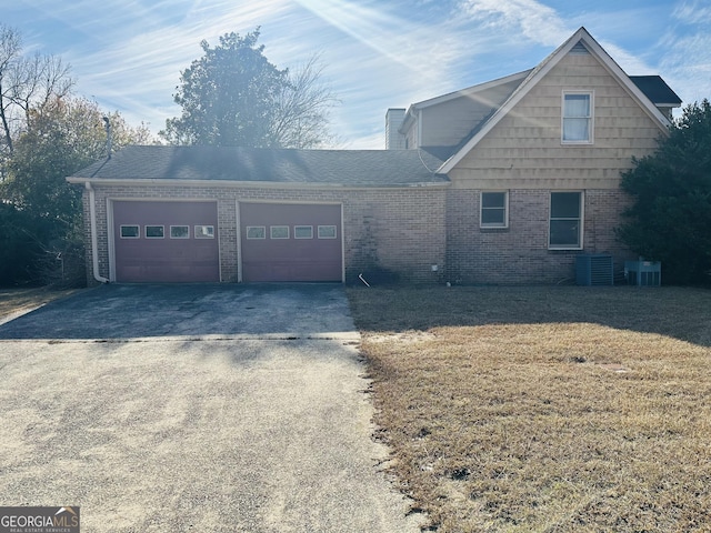 view of front facade with cooling unit, a garage, and a front yard