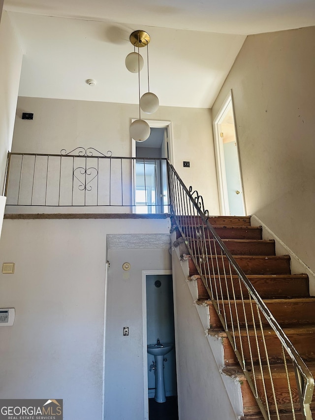 stairway featuring sink and a towering ceiling