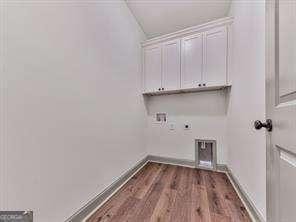 laundry room with electric dryer hookup, hookup for a washing machine, cabinets, and dark hardwood / wood-style flooring