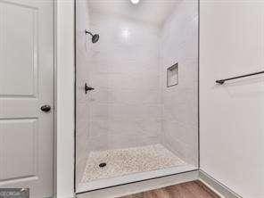 bathroom with tiled shower and hardwood / wood-style floors