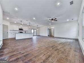 unfurnished living room with ceiling fan and dark hardwood / wood-style flooring