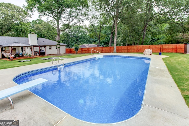 view of pool with a diving board, a deck, and a yard