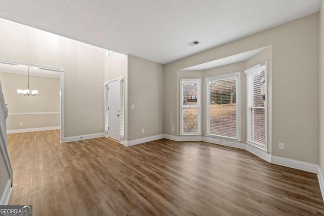 interior space featuring an inviting chandelier, a textured ceiling, and dark hardwood / wood-style floors