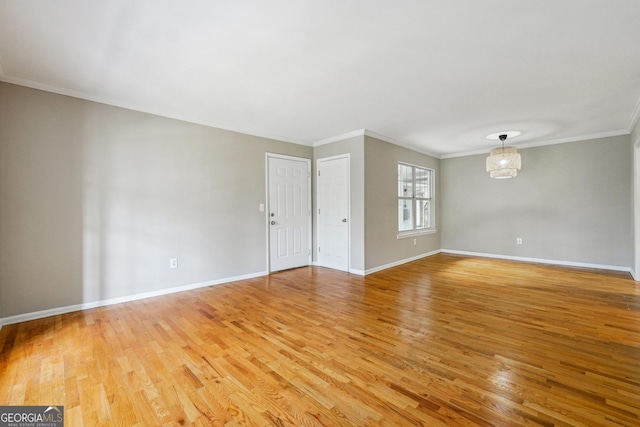 empty room featuring an inviting chandelier, ornamental molding, and wood-type flooring