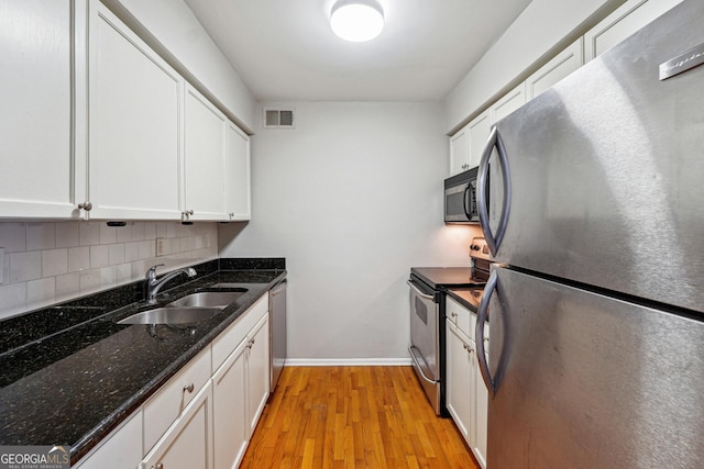 kitchen with white cabinets, appliances with stainless steel finishes, sink, and dark stone countertops