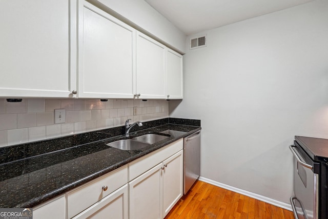 kitchen with white cabinets, dark stone counters, sink, and stainless steel appliances