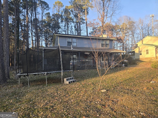 back of house featuring a yard and a trampoline