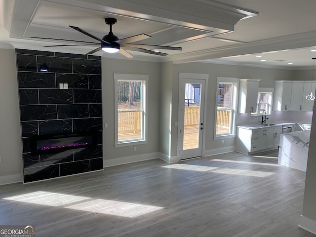 unfurnished living room with a high end fireplace, light hardwood / wood-style floors, crown molding, ceiling fan, and sink