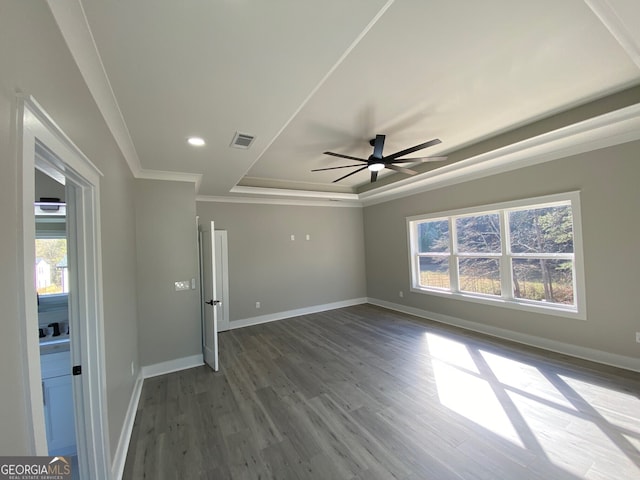 spare room featuring ceiling fan, a tray ceiling, crown molding, and dark hardwood / wood-style flooring