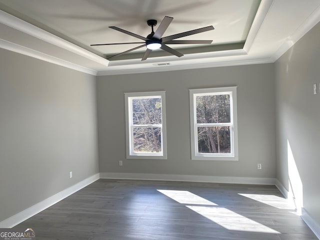 unfurnished room with ornamental molding, ceiling fan, a tray ceiling, and dark hardwood / wood-style floors