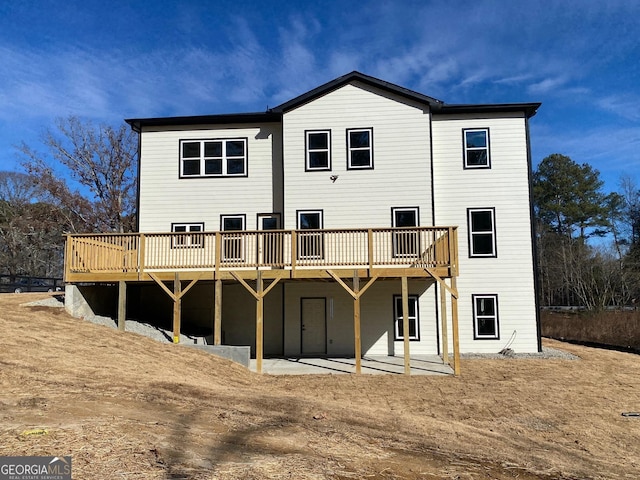 rear view of house featuring a patio area and a wooden deck