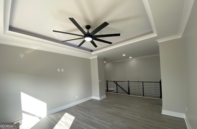 empty room featuring ornamental molding, ceiling fan, a tray ceiling, and hardwood / wood-style floors