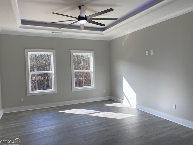 spare room featuring ceiling fan, dark hardwood / wood-style flooring, ornamental molding, and a raised ceiling