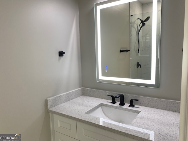 bathroom with a tile shower and vanity