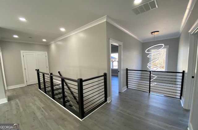 corridor with a chandelier, hardwood / wood-style floors, and ornamental molding