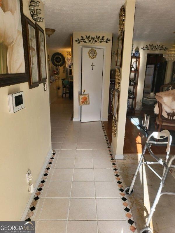 hall with a textured ceiling and light tile patterned flooring