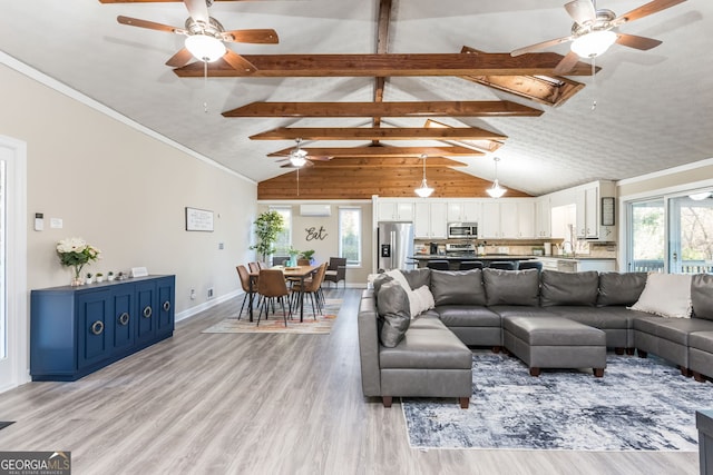 living room featuring a healthy amount of sunlight, light hardwood / wood-style floors, and vaulted ceiling with beams