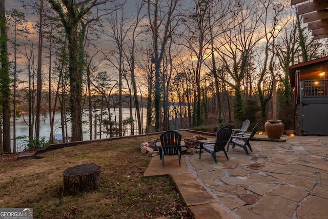 patio terrace at dusk with a water view and a fire pit