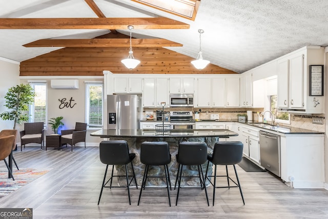 kitchen featuring a kitchen island, white cabinetry, stainless steel appliances, sink, and a wall mounted air conditioner