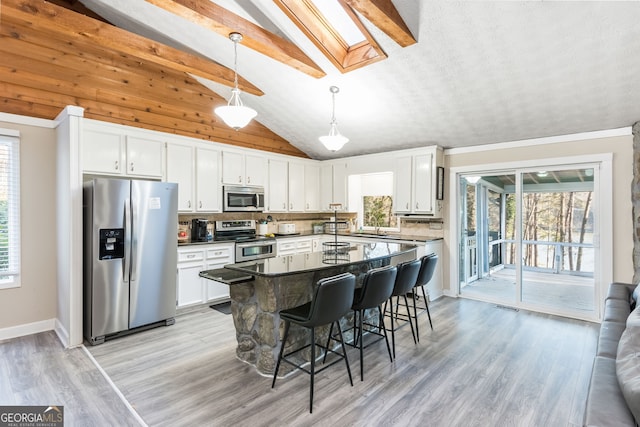 kitchen featuring vaulted ceiling with skylight, white cabinets, and stainless steel appliances