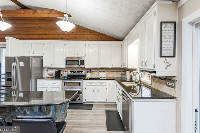 kitchen featuring appliances with stainless steel finishes, sink, hanging light fixtures, white cabinets, and lofted ceiling with beams