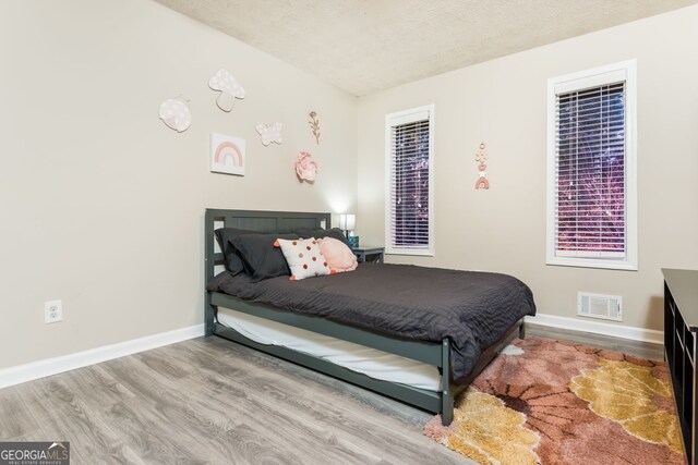 bedroom featuring a textured ceiling and light hardwood / wood-style flooring