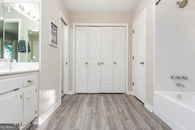 bathroom with vanity, tiled shower / bath, and hardwood / wood-style floors