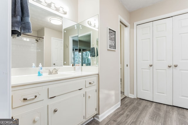 bathroom with hardwood / wood-style flooring, a shower, and vanity