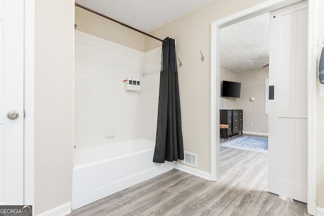 bathroom featuring a textured ceiling, hardwood / wood-style flooring, and shower / bath combo with shower curtain