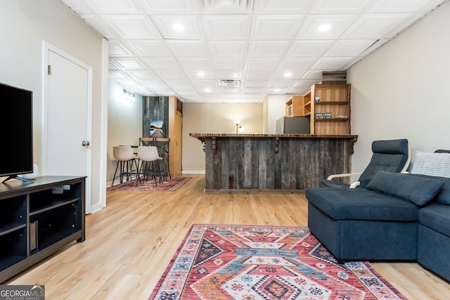 living room with indoor bar and light hardwood / wood-style floors