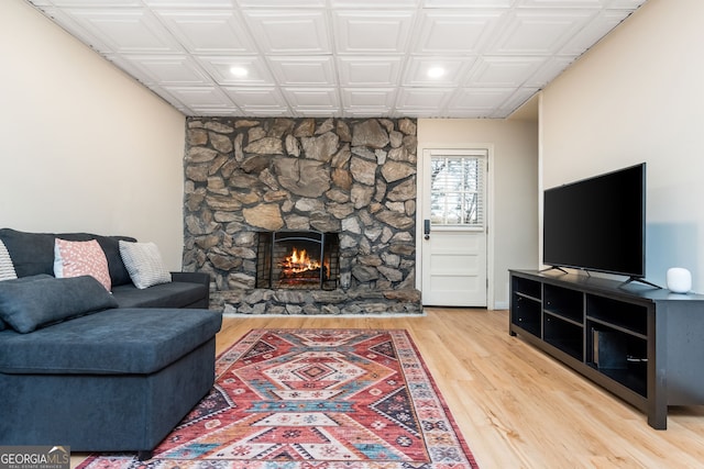 living room with a stone fireplace and hardwood / wood-style floors