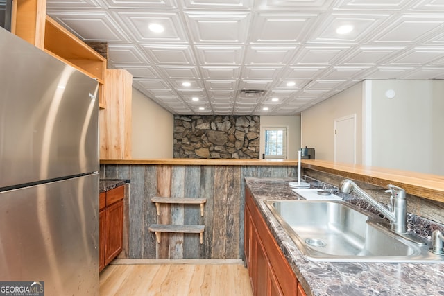 kitchen with sink, light hardwood / wood-style floors, and stainless steel refrigerator