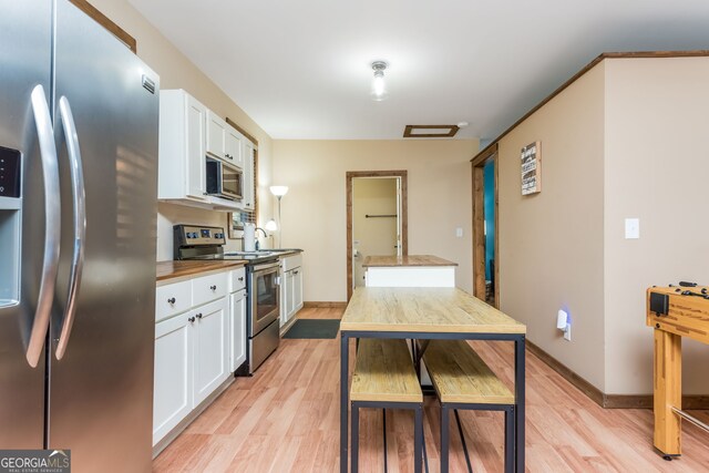 kitchen featuring white cabinetry, butcher block counters, light hardwood / wood-style flooring, and stainless steel appliances