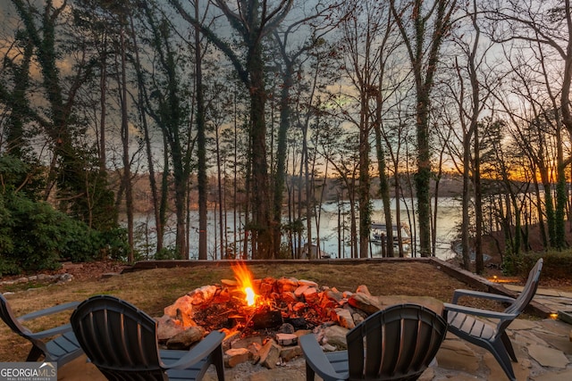 patio terrace at dusk with a water view and a fire pit