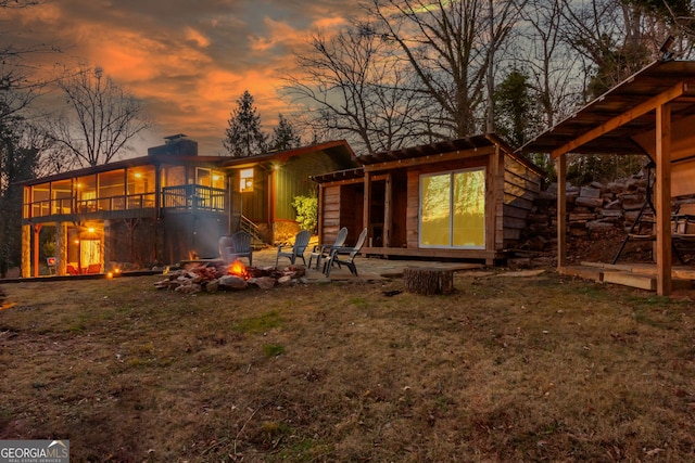 back house at dusk with a patio area, an outdoor fire pit, and a yard