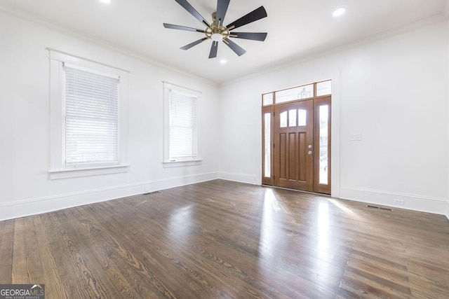 foyer entrance featuring dark wood-type flooring, ceiling fan, a wealth of natural light, and ornamental molding