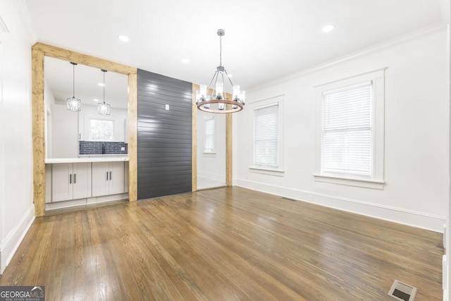 interior space with dark wood-type flooring, ornamental molding, and a chandelier