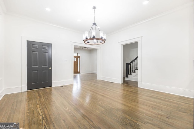 unfurnished dining area featuring an inviting chandelier, crown molding, and dark wood-type flooring