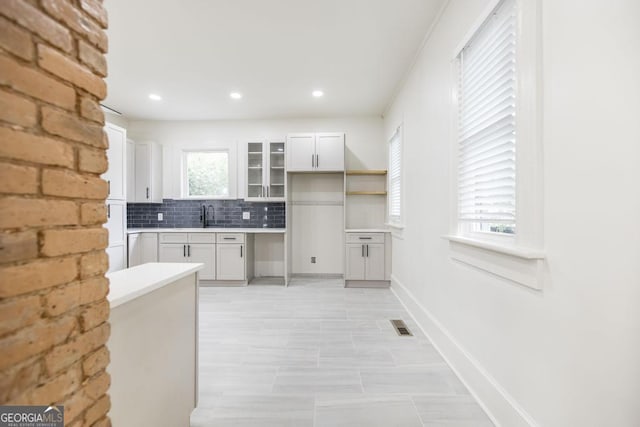 kitchen featuring sink, backsplash, and white cabinetry