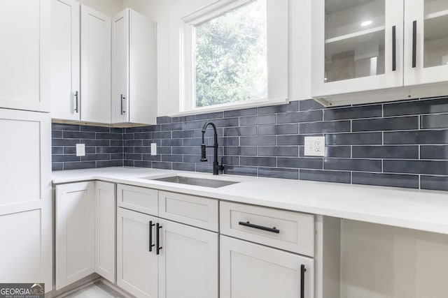 kitchen featuring white cabinetry, backsplash, and sink