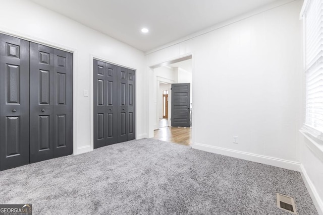 unfurnished bedroom with multiple closets and light carpet