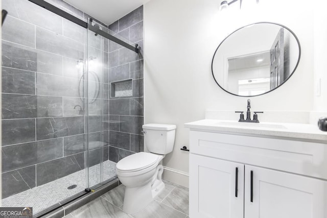 bathroom featuring toilet, vanity, and a shower with shower door