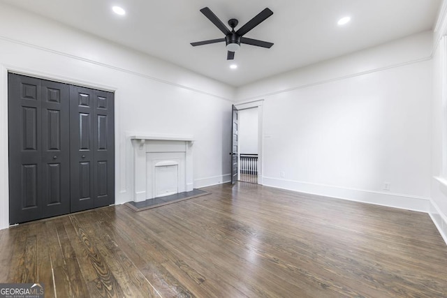 unfurnished living room featuring ceiling fan and dark wood-type flooring