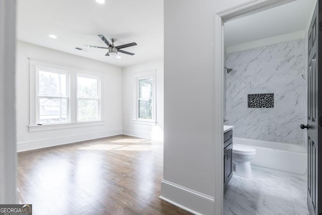 full bathroom with wood-type flooring, toilet, vanity, ceiling fan, and tiled shower / bath